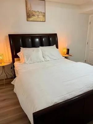 a bedroom with a large bed with a black headboard at Cozy 1-Bed Basement Suite in Calgary
