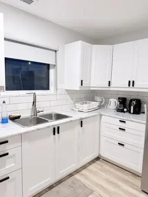 a white kitchen with white cabinets and a sink at Private 1BR Suite with Kitchen, Laundry, Parking & 1 Gigabit Internet in Whitehorse