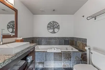 a bathroom with a tub and a sink and a toilet at Serene 2BR Hideaway Hot Tub and Breathtaking Views in Canmore