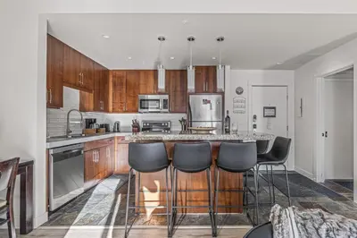 a kitchen with wooden cabinets and a bar with stools at Serene 2BR Hideaway Hot Tub and Breathtaking Views in Canmore