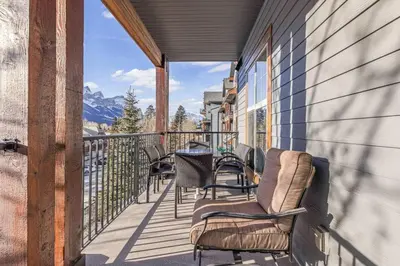 a balcony with chairs and a table and mountains at Serene 2BR Hideaway Hot Tub and Breathtaking Views in Canmore