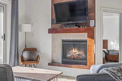 a living room with a fireplace with a tv above it at Serene 2BR Hideaway Hot Tub and Breathtaking Views in Canmore