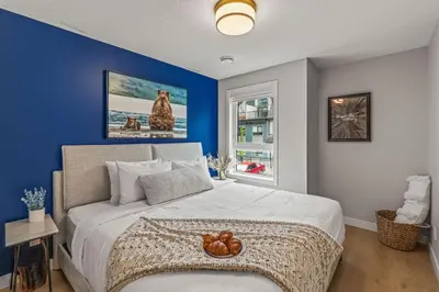 a bedroom with a large bed with a blue wall at 3BR Canmore Haven w/ BBQ and free parking in Canmore