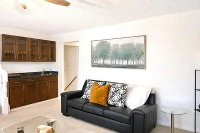 a living room with a black couch and a kitchen at 4-Level Split Home in Southeast Edmonton in Edmonton