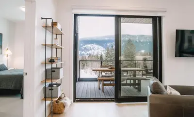 a living room with a view of a table and a balcony at Ridgeline Penthouse by Revelstoke Vacations in Revelstoke