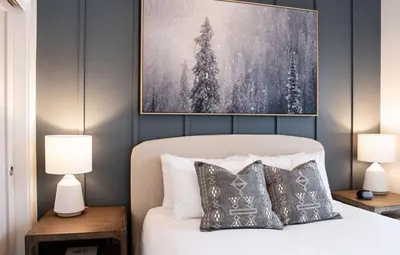 a bedroom with a bed with two lamps and a painting at Powder and Par Penthouse by Revelstoke Vacations in Revelstoke