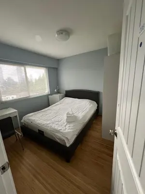 a small bedroom with a bed and a window at Brentwood Home in Burnaby