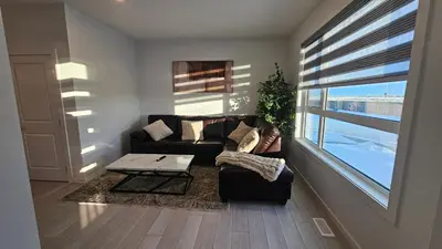 a living room with a couch and a table and a window at 3 Bedroom Modern Luxury House - Family Friendly, 3 Queen Beds, Free Wi-Fi, and Free Parking in Calgary