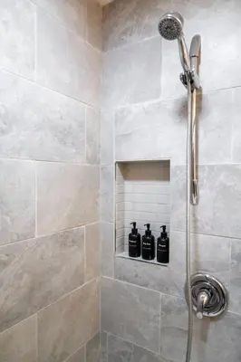 a bathroom with a shower with black bottles on a shelf at Modern 3Bed Home with Fireplace, Game Room, and Stylish Comfort Just 12 Minutes from Downtown Calgary in Calgary