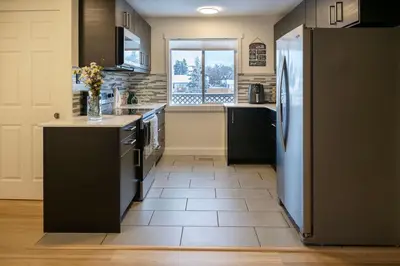 a kitchen with a refrigerator and a tile floor at Modern 3Bed Home with Fireplace, Game Room, and Stylish Comfort Just 12 Minutes from Downtown Calgary in Calgary