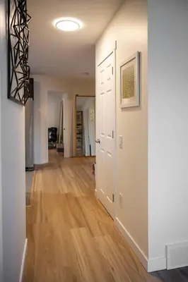an empty hallway in a home with wood floors at Modern 3Bed Home with Fireplace, Game Room, and Stylish Comfort Just 12 Minutes from Downtown Calgary in Calgary