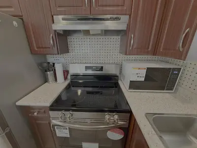 a small kitchen with a stove and a sink at Cozy 2 Bdrm suite in the Heart of Renfrew Heights in Vancouver