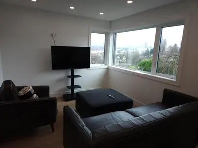 a living room with a couch and a flat screen tv at The Rupert Split Flexible Family Living in Vancouver