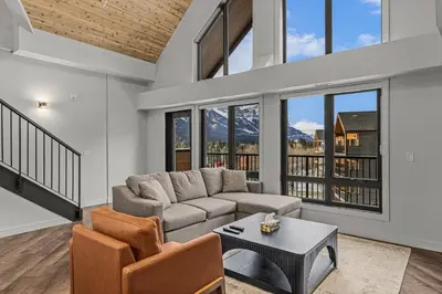 a living room with a couch and a table at Penthouse Loft| 2BD| Mountain Views| Pool + HotTub in Canmore