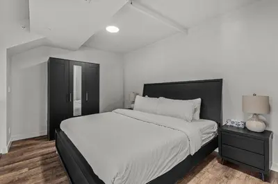 a white bedroom with a large bed and a nightstand at Penthouse Loft| 2BD| Mountain Views| Pool + HotTub in Canmore