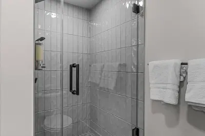 a bathroom with a shower with a toilet and towels at Penthouse Loft| 2BD| Mountain Views| Pool + HotTub in Canmore