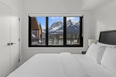 a bedroom with a bed and a view of a mountain at Premier Suite | Mountain Views | Sleeps 10 in Canmore