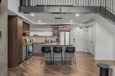 a kitchen with a counter and stools in it at Premier Suite & Penthouse Loft - Sleeps 16 in Canmore