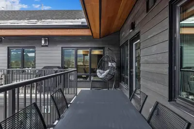 a deck with a table and chairs on a house at Premier Suite & Penthouse Loft - Sleeps 16 in Canmore