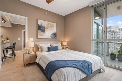 a bedroom with a bed and a large window at Bright and Comfortable 2BR Downtown Apartment for Families and Groups in Vancouver