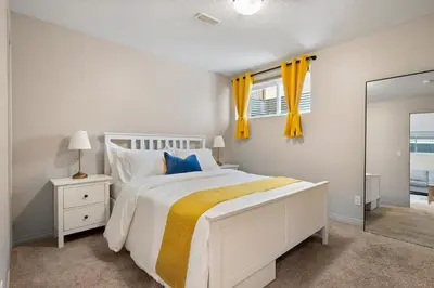 a white bedroom with a bed and a mirror at Panorama Hills Cozy Guest Suite in Calgary