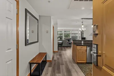 a kitchen and living room with a bench and a table at Tranquil Condo In The Trees Spacious 2Bd Hot Tub & Pool in Canmore