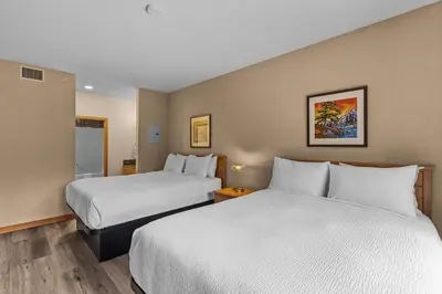 a hotel room with two beds with white sheets at Tranquil Condo In The Trees Spacious 2Bd Hot Tub & Pool in Canmore