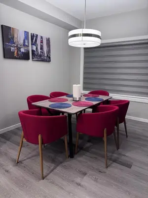 a dining room with a table and red chairs at NorthEdge Master Suite, Leduc in Leduc
