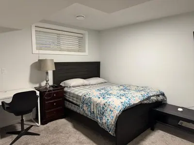 a bedroom with a bed and a desk and a chair at Cozy 2 Bedroom Basement Apartment in Calgary