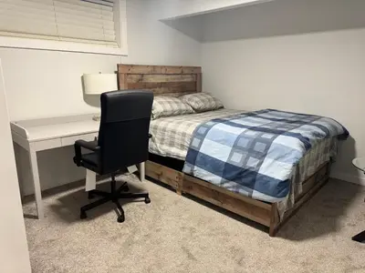 a bedroom with a bed and a desk and a chair at Cozy 2 Bedroom Basement Apartment in Calgary