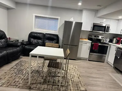 a living room with a black couch and a white table at Cozy 2 Bedroom Basement Apartment in Calgary