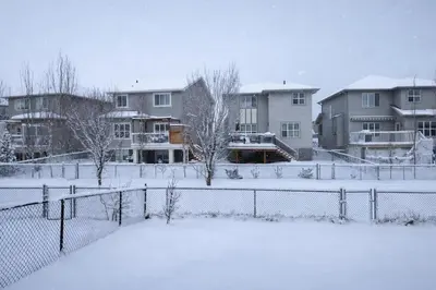 a snow covered yard with houses and a fence at Private Suite in Airdrie Near Calgary Free Parking in Airdrie