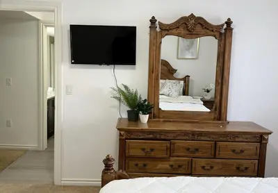 a bedroom with a dresser with a mirror and a bed at Private Suite in Airdrie Near Calgary Free Parking in Airdrie