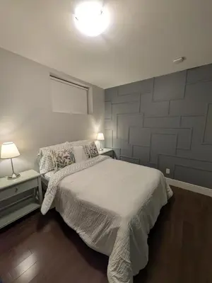 a bedroom with a white bed and two tables with lamps at Designer 2-Bedroom Garden-Level Walk-Out Suite in Surrey