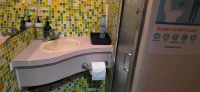 a bathroom with a sink and a yellow tiled wall at Shangri-la Joy in Vancouver