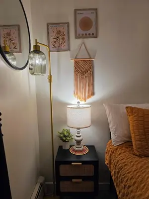 a lamp on a night stand next to a bed at Small Town Pearl l Charming & Cozy 2 Level Suite Near Red Deer l Yard & BBQ in Penhold