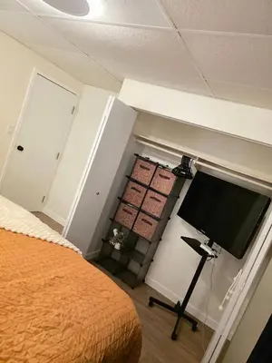 a bedroom with a bed and a flat screen tv at Small Town Pearl l Charming & Cozy 2 Level Suite Near Red Deer l Yard & BBQ in Penhold