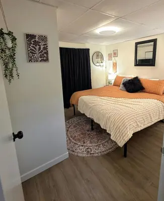a bedroom with a bed with two cats laying on it at Small Town Pearl l Charming & Cozy 2 Level Suite Near Red Deer l Yard & BBQ in Penhold