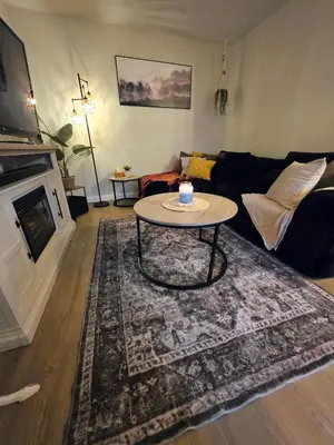 a living room with a table and a couch at Small Town Pearl l Charming & Cozy 2 Level Suite Near Red Deer l Yard & BBQ in Penhold