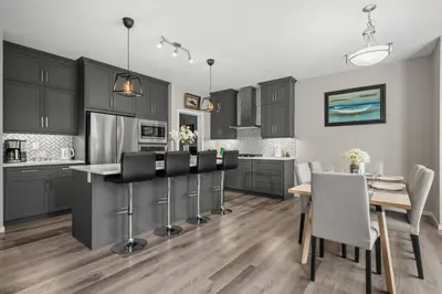 a kitchen with black cabinets and a table with chairs at Bright & Spacious Family Retreat in Calgary