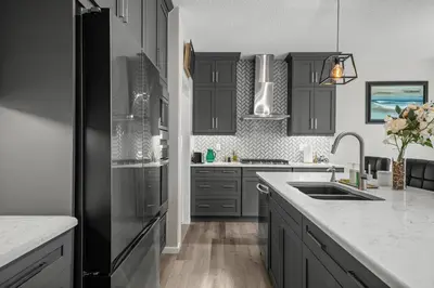 a kitchen with gray cabinets and a black refrigerator at Bright & Spacious Family Retreat in Calgary