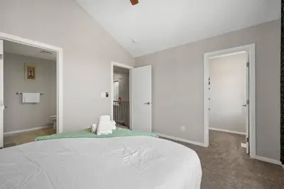a white bedroom with a bed and a bathroom at Bright & Spacious Family Retreat in Calgary