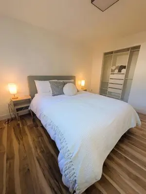 a bedroom with a large white bed with two lamps at Private room in Chic Main St suite in Vancouver