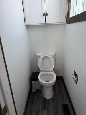 a small bathroom with a toilet and a cabinet at Cowboy Cabin- Lakefront Rental Northern Saskatchewan