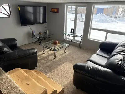 a living room with two leather couches and a tv at Cowboy Cabin- Lakefront Rental Northern Saskatchewan