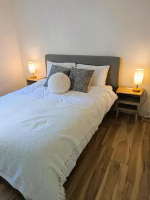 a bedroom with a bed with pillows and two lamps at 2 bedroom suite close to Main and Skytrain in Vancouver