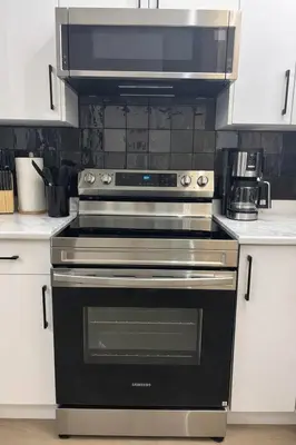 a kitchen with a black oven and a microwave at The Bear Cave - Artist-Inspired Suite in Langford