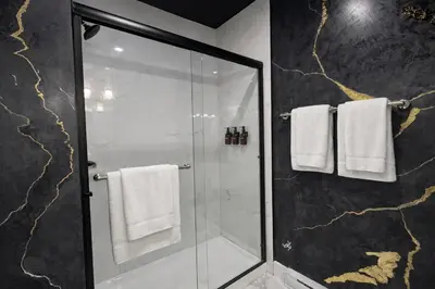a bathroom with a shower with white towels at The Bear Cave - Artist-Inspired Suite in Langford