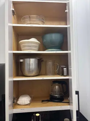 a kitchen cabinet filled with bowls and utensils at The Bear Cave - Artist-Inspired Suite in Langford