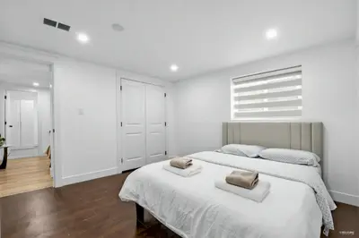 a white bedroom with a large bed with two pillows on it at Shanaz house in Vancouver